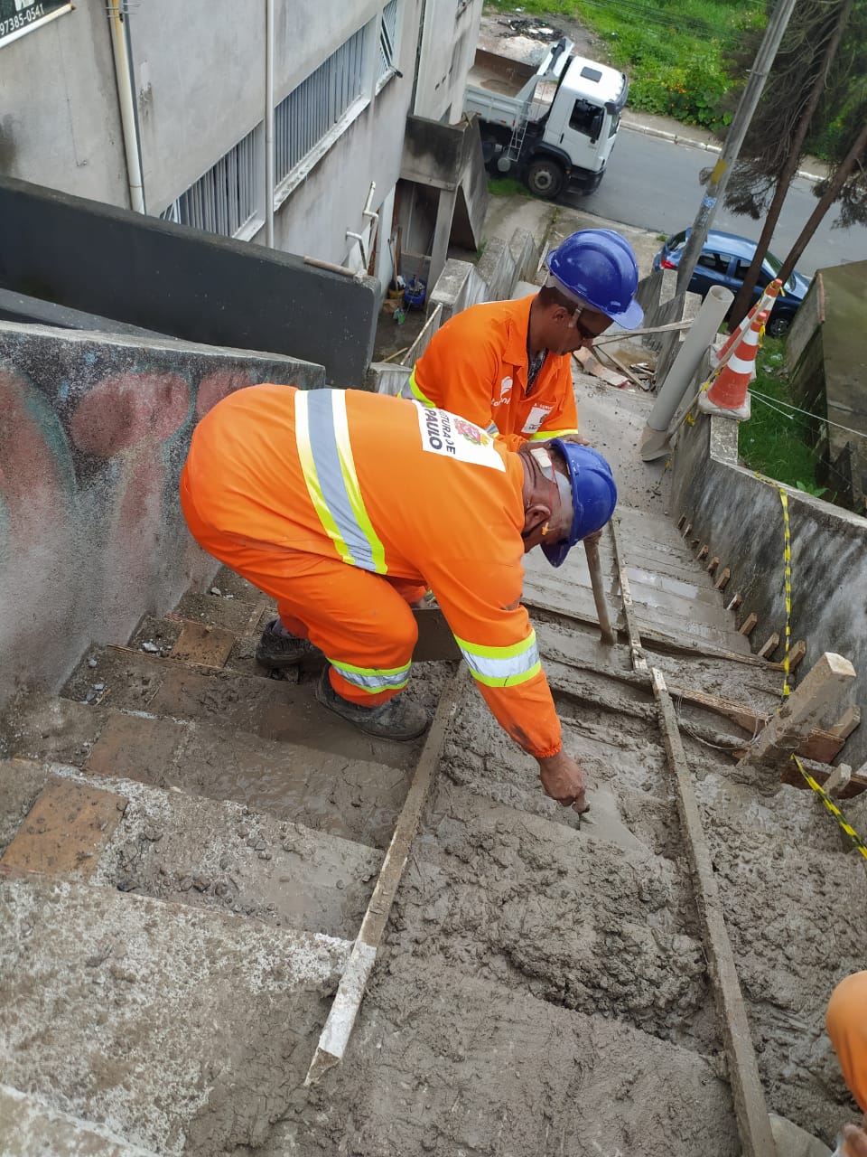 Trabalhadores espalham concreto nos degraus do escadão da rua José Juarez Antunes